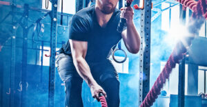 Image of a man in the gym using battle ropes