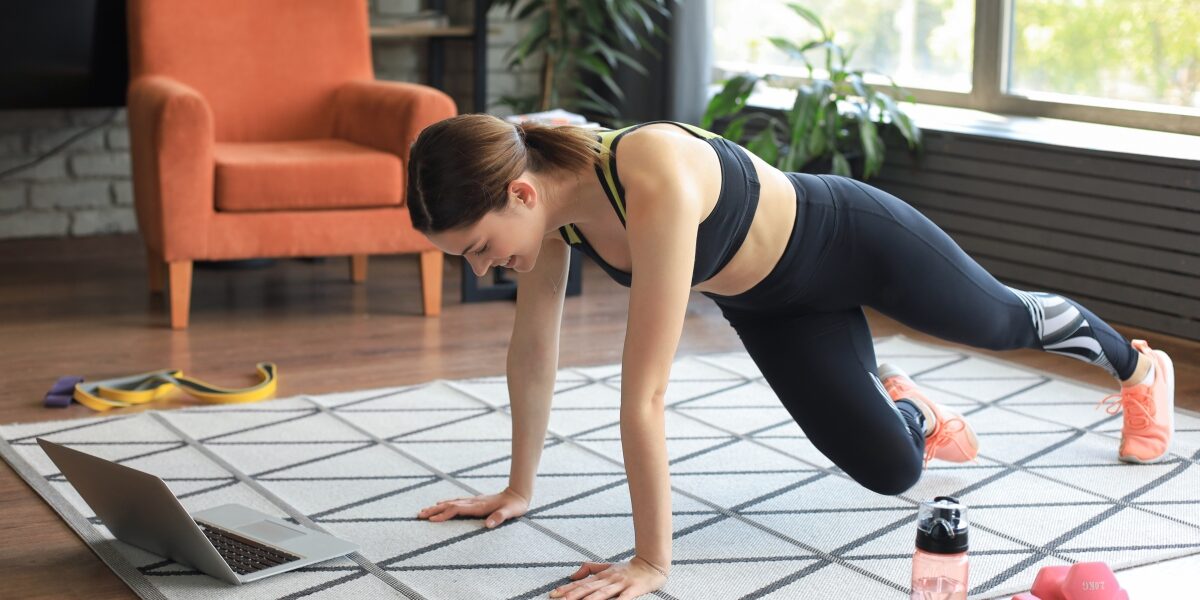 Woman working out at home to online fitness class